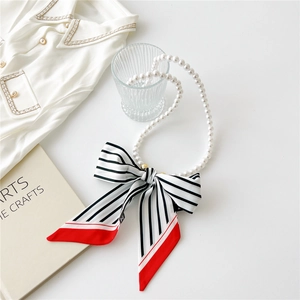 Detail of French vintage pearl necklace with a black and white striped silk scarf bow