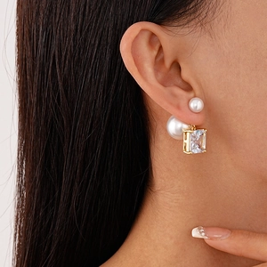 Détail d'une boucle d'oreille en or avec perles blanches et zircon carré sur modèle