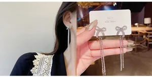 Detail of silver S925 bow earrings featuring long chain tassels and sparkling zircon stones