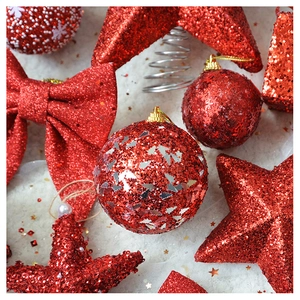 Close-up of glittery red Christmas ornaments with star and bow shapes on white fur