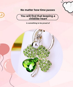 Close-up of four-leaf clover keychain with green crystal gemstone and silver plating
