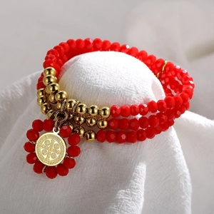 Detailed view of triple-layer red glass beads bracelet with gold St. Benedict medal