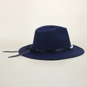 Detail of dark blue fedora hat with black satin ribbon, bow, and a white pearl accent