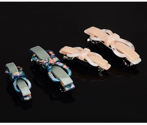 Detail showing acetate bow hair clips in green and beige with sparkling rhinestones