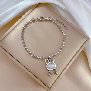 Close-up of silver rabbit charm bracelet with cat eye stone on a golden jewelry pad