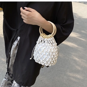 Close-up of handmade white straw bucket bag with wooden ring handles and drawstring liner