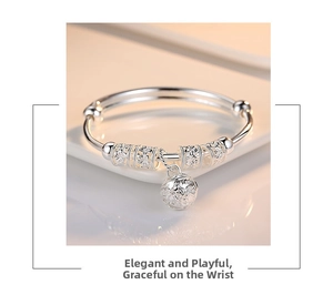 Macro shot of silver adjustable bangle with hollow floral beads and a tinkling bell charm