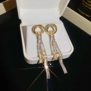Macro detail of gold tassel earrings with shimmering crystals in a luxury gift box