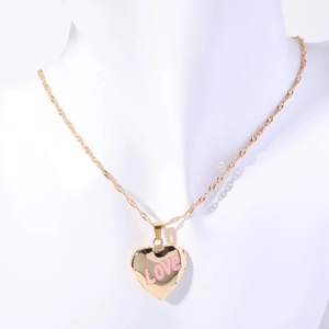 Detail of a gold heart locket necklace with pink LOVE enamel on a white model