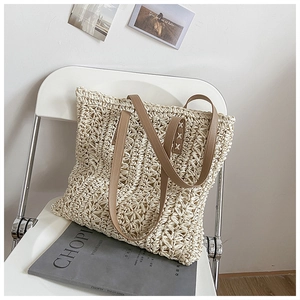 Detailed view of beige hollow-out crochet tote with elegant floral texture and brown leather handles