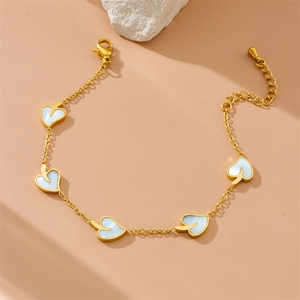 Elegant gold chain bracelet featuring five white heart charms on a textured stone base