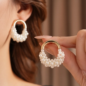 Dettaglio di eleganti orecchini a perla a forma di U con accenti dorati su una modella
