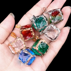 Hand holding assorted colorful cubic crystal pendants with gold and silver plated edges