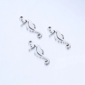 Macro detail of three polished stainless steel seahorse pendants on a brushed metal surface