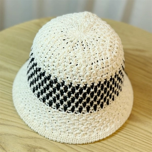 Detail of hand-woven straw bucket hat with black and cream wavy texture and fine stitching