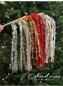 Close-up of glittered Christmas picks in gold, silver, and red against a festive tree