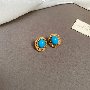 Detail of vintage gold earrings with oval turquoise, white pearls, and zircon accents