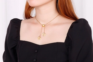 Détail d'un collier en Y doré avec fermoir coeur et pendentifs pingouin sur un mannequin