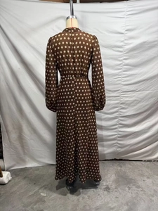 Detailed back view of a long brown polka dot dress with pleated design and high neck