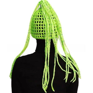 Macro detail of fluorescent green hand-knitted horn hat featuring long braided mesh accents