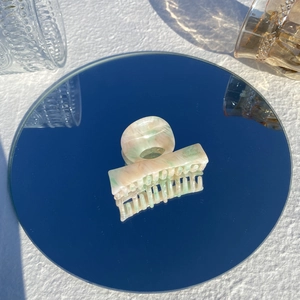 Close-up of marble pattern hair claw clip on mirror surface with natural sunlight