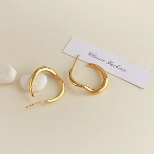 Detailed close-up of 18K gold wave earrings showing polished surface and S925 hallmark