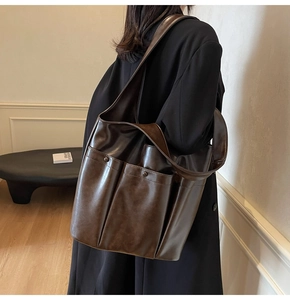 Detail view of a vintage brown leather tote bag with two front pockets on a model