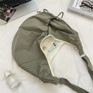 Detail of green plaid nylon bag showing spacious interior with zipper pocket and metal buckle