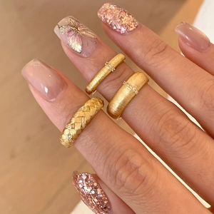 Three gold vintage-style brushed rings with small stones set on a hand model