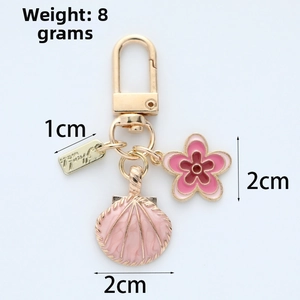 Detail showing pink enamel flower, shell charm and gold keychain dimensions