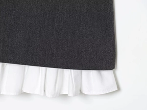 Detail of dark grey fabric texture with white tiered ruffle hem on a mini dress