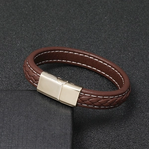 Close-up of brown braided leather bracelet with gold magnetic clasp and white stitching detail