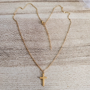 Detail of 18K gold stainless steel cross pendant necklace with fine chain on wood