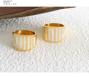 Detail of gold-plated titanium steel rings with shell inlay and vertical stripe texture