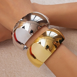 Close-up of wide irregular metallic bracelets in gold and silver mirror finish on wrist
