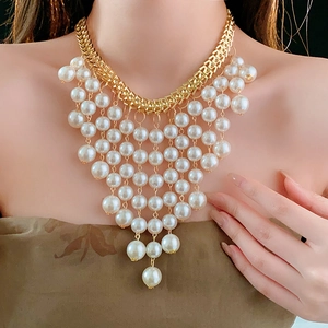 Primo piano della collana a catena dorata con eleganti nappine di perle bianche multistrato