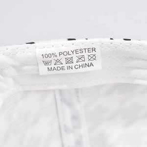 Detail of the internal care label on a houndstooth baseball cap showing 100% polyester fabric
