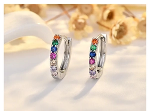 Macro shot of silver hoops with rainbow zircon stones and elegant flower background