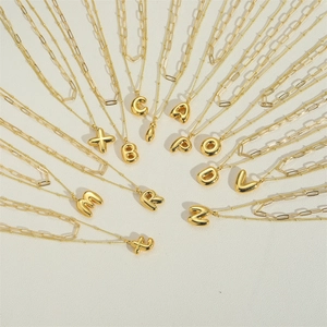 Detailed view of gold layered balloon initial necklaces with paperclip chains and pendants