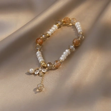 Detail of freshwater pearl bracelet with amber beads and crystal flower pendant