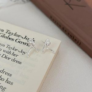 Detailed close-up of bow knot 925 silver earrings with zircon inlay on book page