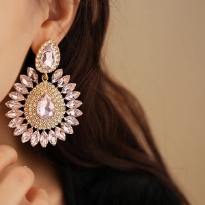 Close-up of luxury gold drop earrings featuring pink pear-cut crystals and marquise stones