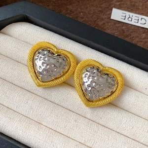 Detail of vintage heart earrings with gold rope edges and hammered silver texture