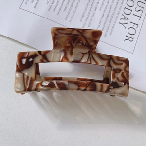 Detailed view of large amber marble rectangular hair claw clip on a stylish magazine