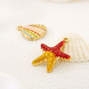 Macro shot of gold starfish and seashell enamel pendants with vibrant sea life details