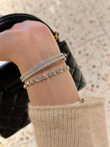 Détail de bracelet jonc et gourmette en argent avec pierres de zircon scintillantes