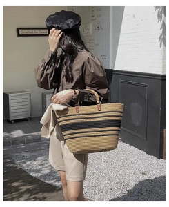Detail of striped woven tote bag with bamboo handles shown in an outdoor setting