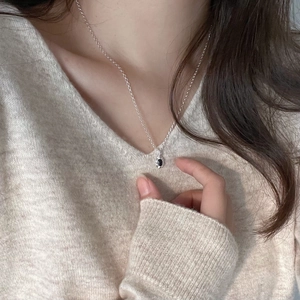 Detail of 925 sterling silver necklace featuring a black zircon pendant on a model neck