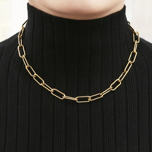 Close-up of golden paperclip chain necklace worn over a black turtleneck sweater