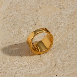 Macro close-up of a wide polished 18K gold-plated stainless steel sun ring on a stone surface